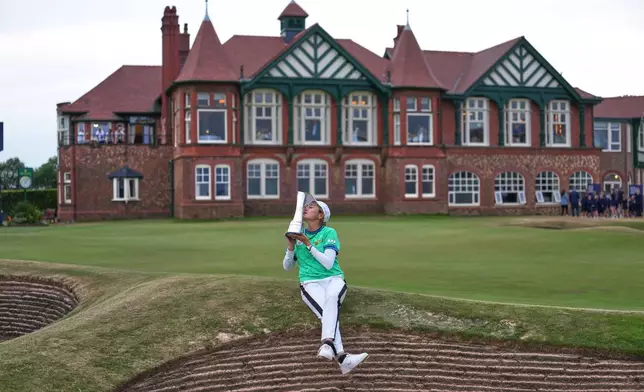 Shiho Kuwaki, of Japan, kisses the trophy as she poses for the media after winning the Women's British Open golf championship in Lytham St Annes, England, Sunday, Aug. 2, 2026. (AP Photo/Jon Super)