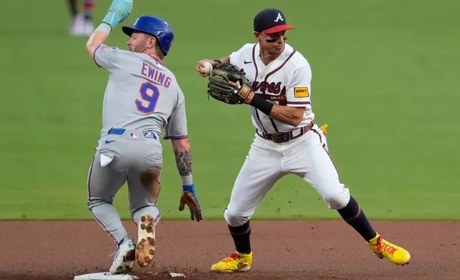 Atlanta Braves left fielder Mauricio Dubón (14) makes the tag on New York Mets' A.J. Ewing (9) in the first inning of a baseball game, Wednesday, Aug. 12, 2026, in Atlanta. (AP Photo/Mike Stewart)