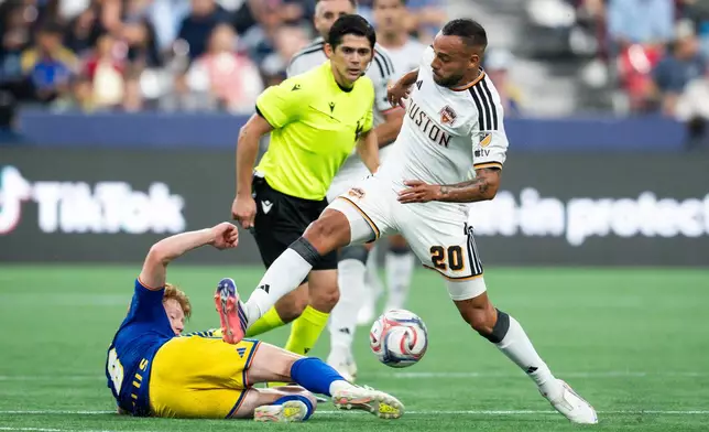 Vancouver Whitecaps' Oliver Larraz (bottom left) tackles Houston Dynamo FC's Guilherme Santos (20) during the first half of an MLS soccer match in Vancouver, B.C., on Wednesday, Aug. 19, 2026. (Ethan Cairns/The Canadian Press via AP)