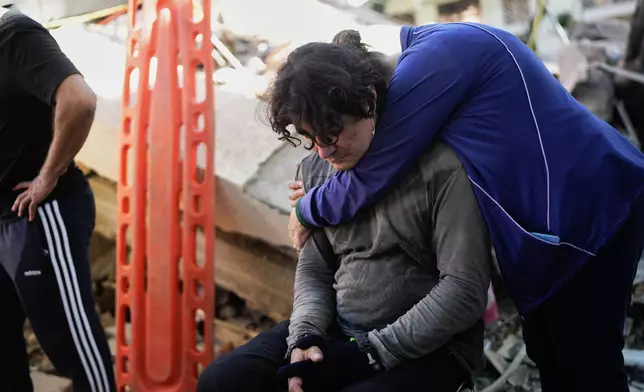 Neighbors embrace as rescue workers search through the rubble of a collapsed apartment building the day after an earthquake struck Cali, Colombia, Tuesday, Aug. 11, 2026. (AP Photo/Ivan Valencia)