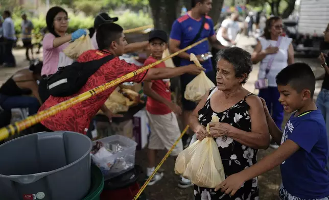 People affected by the earthquake receive food packages in Cali, Colombia, Wednesday, Aug. 12, 2026. (AP Photo/Ivan Valencia)