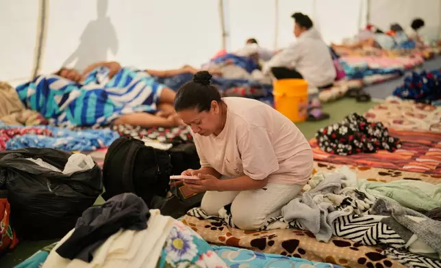 A woman checks her mobile phone at a temporary shelter for people whose homes were damaged after an earthquake struck Pereira, Colombia, Wednesday, Aug. 12, 2026. (AP Photo/Fernando Vergara)
