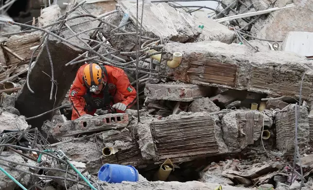 A Mexican rescue worker searches through the rubble two days after an earthquake struck Cali, Colombia, Wednesday, Aug. 12, 2026. (AP Photo/Santiago Saldarriaga)