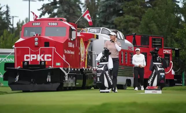 Miyu Yamashita, back right, of Japan, walks past a mini CPKC train as she arrives at the first tee behind Hannah Green, of Australia, during the first round at the LPGA Canadian Women's Open golf tournament in Edmonton, Alberta, Thursday, Aug. 20, 2026. (Darryl Dyck/The Canadian Press via AP)