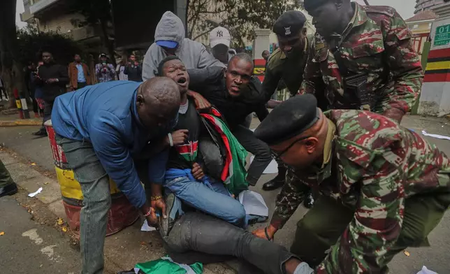 Police officers detain an activist during a demonstration over alleged abductions and extrajudicial killings, outside the office of Kenya's Inspector General of Police Douglas Kanja, in Nairobi, Kenya, Monday, Aug. 17, 2026. (AP Photo/Henry Naminde)