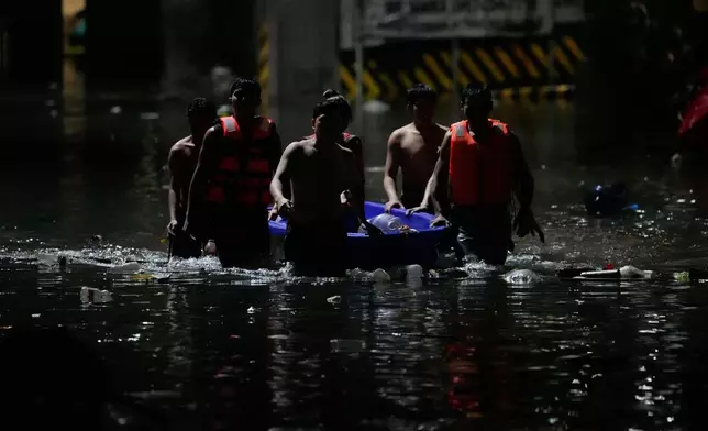 Men push a small boat to help residents along a flooded street caused by intense monsoon rains in Quezon city, Metro Manila, Philippines Monday, Aug. 17, 2026. (AP Photo/Aaron Favila)