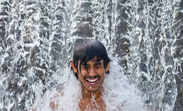 A migrant worker from Sri Lanka cools off in a cascading river on a torrid day, outside Bragadiru, Romania, Tuesday, Aug. 18, 2026. (AP Photo/Andreea Alexandru)