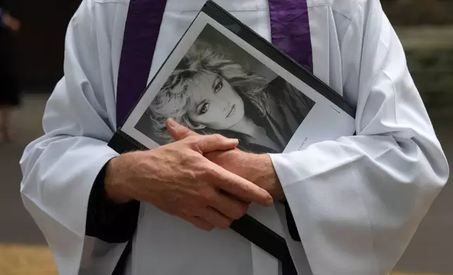 An unidentified priest holds a Bonnie Tyler poster outside St. Mary's Church in Swansea, Wales, Monday, Aug. 17, 2026 before the service and funeral of the musician, whose real name was Gaynor Hopkins. (AP Photo/Alastair Grant)