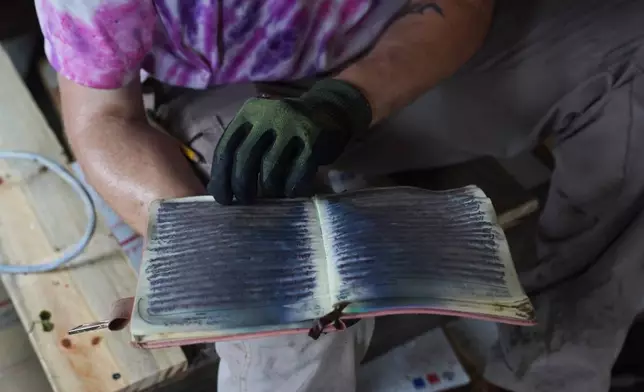 Oliver Riggle holds a water-soaked journal inside his flooded trailer in Indianapolis, Monday, Aug. 17, 2026. (AP Photo/Obed Lamy)