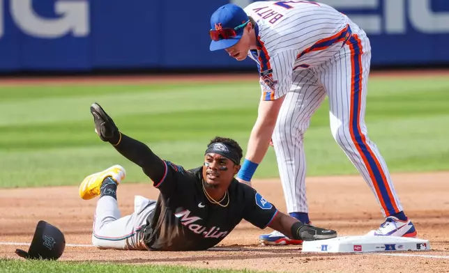 Miami Marlins' Esteury Ruiz , bottom, reacts after sliding to third base past New York Mets third baseman Brett Baty, top, during the second inning of a baseball game, Saturday, Aug. 1, 2026, in New York. (AP Photo/Heather Khalifa)