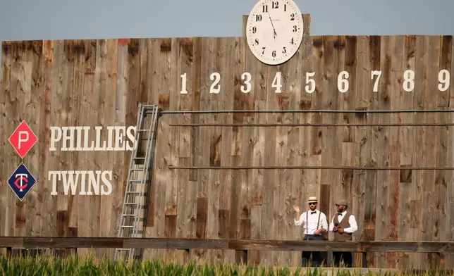 Scoreboard workers look on before a baseball game between the Minnesota Twins and the Philadelphia Phillies at the Field of Dreams movie site, Thursday, Aug. 13, 2026, in Dyersville, Iowa. (AP Photo/Charlie Neibergall)