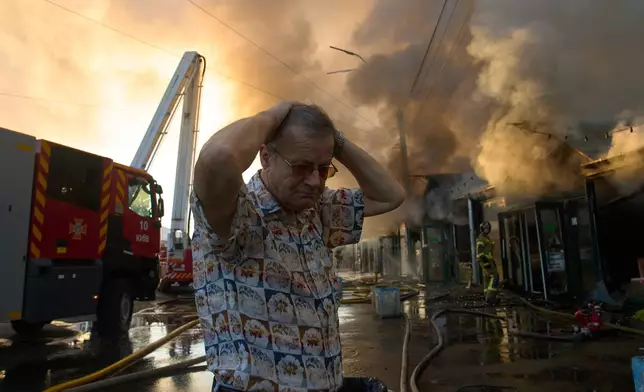 Bookseller Alexander Bahlai reacts as firefighters try to put out a fire at a city book market following a Russian missile attack in Kyiv, early Sunday, Aug. 16, 2026. (AP Photo/Francisco Seco)