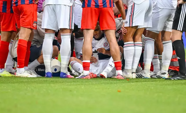 Bayern's Jamal Musiala, center, sits on the ground during a friendly soccer match between FC Heidenheim and FC Bayern Munich in Heidenheim, Germany, Tuesday, Aug. 18, 2026. (Harry Langer/DeFodi/dpa via AP)