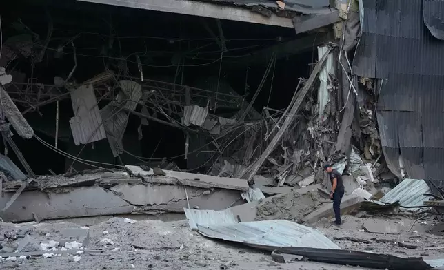 A police officer examines a damaged Nova Poshta postal warehouse after Russian missiles strikes in Kyiv, Ukraine, Wednesday, Aug. 5, 2026. (AP Photo/Efrem Lukatsky)