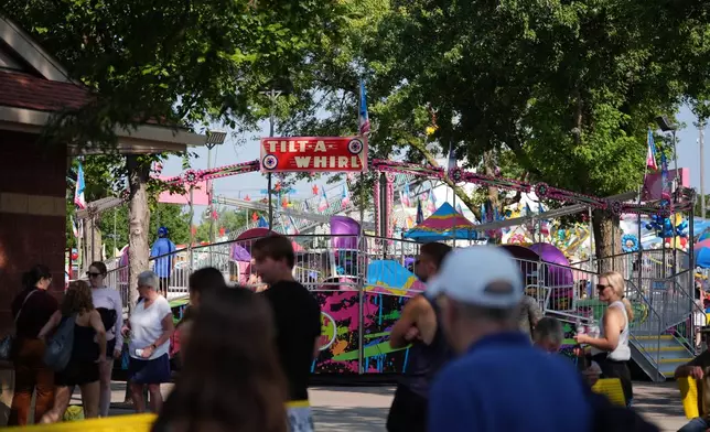 Fairgoers pass the Tilt-A-Whirl, Thursday, Aug. 27, 2026, at the Minnesota State Fair in Falcon Heights, Minn. (AP Photo/Ellen Schmidt)