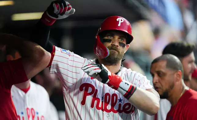 Philadelphia Phillies' Bryce Harper celebrates in the dugout after hitting a solo home run off Toronto Blue Jays pitcher Max Scherzer during the sixth inning of a baseball game, Saturday, Aug. 8, 2026, in Philadelphia. (AP Photo/Derik Hamilton)