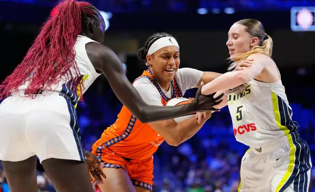 Connecticut Sun's Nell Angloma, center, drives to the basket against Dallas Wings' Awak Kuier, left, and Paige Bueckers (5) during the first half of a WNBA basketball game in Arlington, Texas, Sunday, Aug. 2, 2026. (AP Photo/Tony Gutierrez)