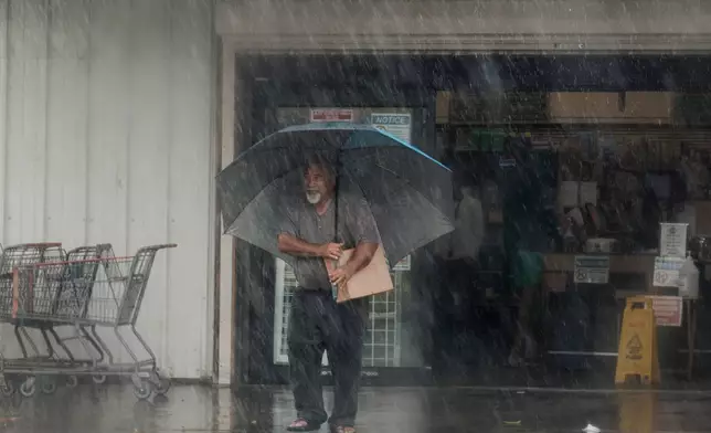 A resident carries supplies during Hurricane Lala in Hawaiian Ocean View, Hawaii, Saturday, Aug. 15, 2026. (Stephen Lam/San Francisco Chronicle via AP)