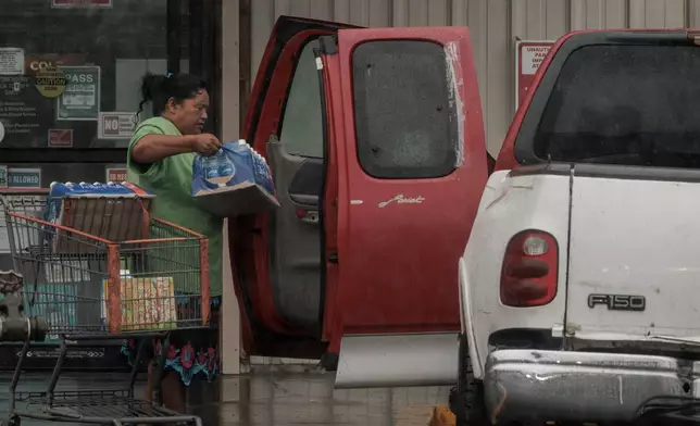A resident carries supplies to a vehicle during Hurricane Lala in Hawaiian Ocean View, Hawaii, Saturday, Aug. 15, 2026. (Stephen Lam/San Francisco Chronicle via AP)