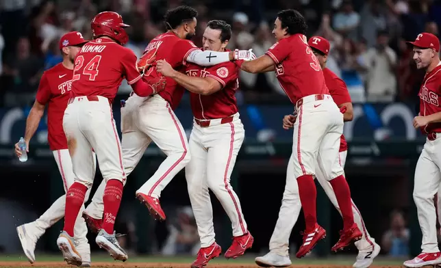 Texas Rangers' Brandon Nimmo (24), Ezequiel Duran, second from left, Wyatt Langford, Nicky Lopez, right front, and the rest of the team celebrate Duran's run-scoring single in the 10th inning of a baseball game against the Los Angeles Angels Friday, Aug. 21, 2026, in Arlington, Texas. (AP Photo/Tony Gutierrez)