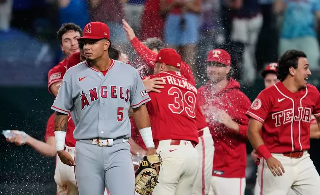 Los Angeles Angels left fielder Vaughn Grissom (5) walks away as the Texas Rangers celebrate a run-scoring single by Ezequiel Duran in the 10th inning of a baseball game Friday, Aug. 21, 2026, in Arlington, Texas. (AP Photo/Tony Gutierrez)