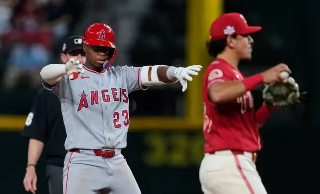 Los Angeles Angels' Denzer Guzman (23) celebrates his run-scoring double in front of Texas Rangers second baseman Nicky Lopez as umpire Alex Tosi, rear, looks on in the 10th inning of a baseball game Friday, Aug. 21, 2026, in Arlington, Texas. (AP Photo/Tony Gutierrez)