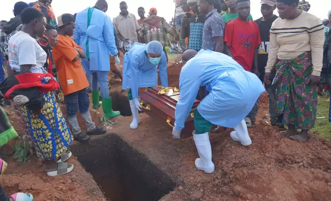 People dressed in protective gear prepare to lower into a grave the coffin containing the remains of 3-year-old Mave Mercienne, who died of Ebola, in Bunia, Ituri province, eastern Congo, Tuesday, Aug. 18, 2026. (AP Photo/Dieudonne Dirole)