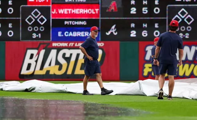 Members of the Cleveland Guardians grounds crew remove a tarp from the field during a rain delay before a baseball game against the San Diego Padres in Cleveland, Sunday, Aug. 16, 2026. (AP Photo/Tim Phillis)