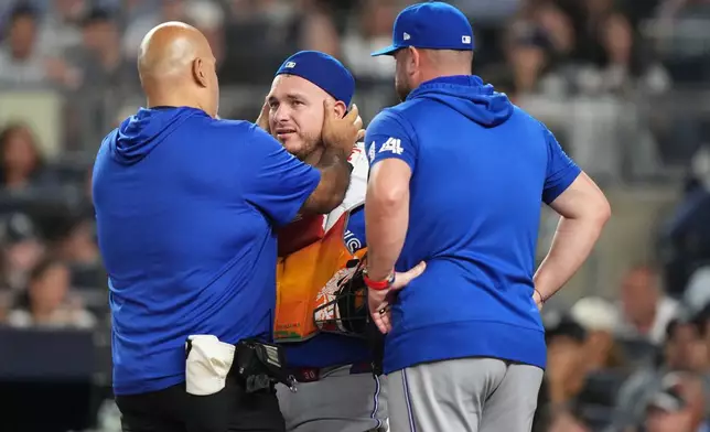 Toronto Blue Jays manager John Schneider, right, watches as a trainer checks on catcher Alejandro Kirk during the third inning of a baseball game against the New York Yankees Friday, Aug. 21, 2026, in New York. (AP Photo/Frank Franklin II)