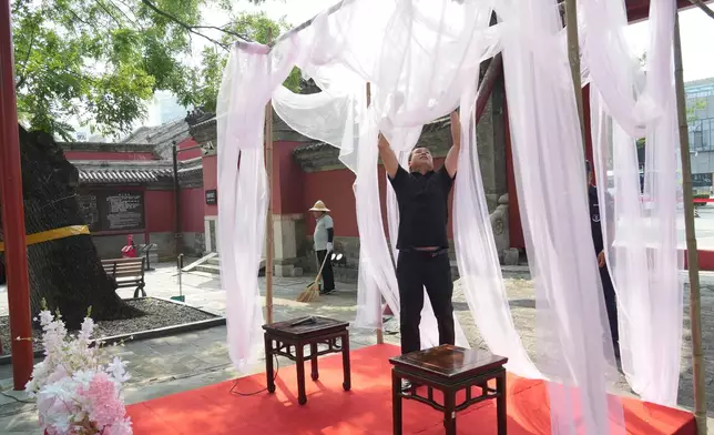 A worker decorates ahead of a festival to celebrate Qixi at the Beijing Folk Custom Museum in Beijing, Wednesday, Aug. 19, 2026. (AP Photo/Achmad Ibrahim)