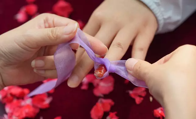A woman gets her nail dyed with garden balsam, a natural pigment traditionally associated with beauty and blessings, during a festival to celebrate Qixi at the Beijing Folk Custom Museum in Beijing, Wednesday, Aug. 19, 2026. (AP Photo/Achmad Ibrahim)