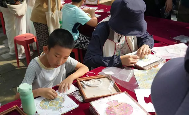 A child makes a sachet-shaped Song brocade pearl painting during a festival to celebrate Qixi at the Beijing Folk Custom Museum in Beijing, Wednesday, Aug. 19, 2026. (AP Photo/Achmad Ibrahim)