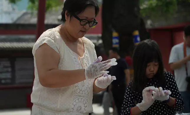 Wang Xuejie and her 7-year-old daughter make qiaoguo, a pastry made by pressing dough into decorative molds, during a festival to celebrate Qixi at the Beijing Folk Custom Museum in Beijing, Wednesday, Aug. 19, 2026. (AP Photo/Achmad Ibrahim)