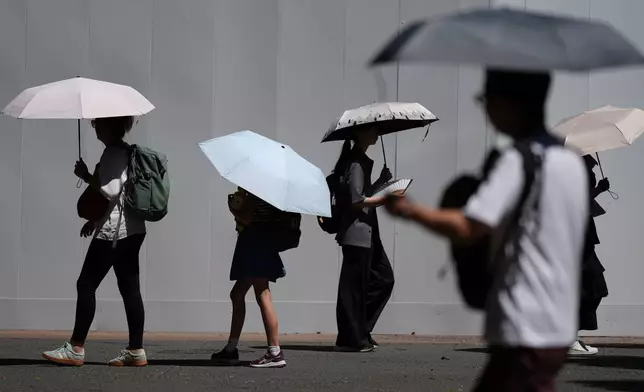 People use umbrellas to shield themselves from the scorching sun Tuesday, Aug. 25, 2026, in Tokyo. (AP Photo/Eugene Hoshiko)