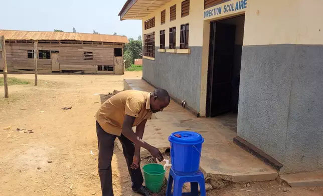 A parent who came for his child's school resumption washes his hands outside a school in Ituri province, eastern Congo, Thursday, Aug. 27, 2026. (AP Photo/Constant Same Bagalwa)