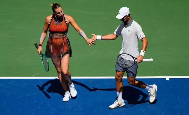 Aryna Sabalenka, of Belarus, and Novak Djokovic, of Serbia, high-five during a mixed doubles match at the U.S. Open tennis championships, Tuesday, Aug. 25, 2026, in New York. (AP Photo/Yuki Iwamura)