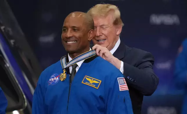 President Donald Trump participates in a Congressional Space Medal of Honor ceremony at NASA's Johnson Space Center, Friday, Aug. 28, 2026, in Houston, and puts a medal on Artemis II Astronaut and Pilot Victor Glover. (AP Photo/Karen Warren)