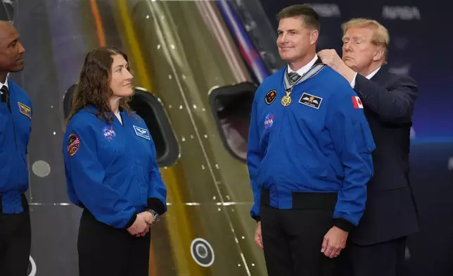 President Donald Trump participates in a Congressional Space Medal of Honor ceremony at NASA's Johnson Space Center, Friday, Aug. 28, 2026, in Houston, and puts a medal on Artemis II Astronaut and Mission Specialist, Jeremy Hansen. (AP Photo/Karen Warren)