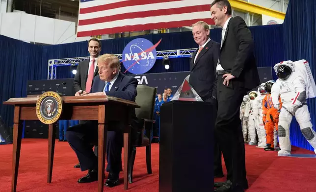 President Donald Trump signs an executive order creating the U.S. Space Academy as Michael Kratsios, White House Science and Technology advisor, from left, Kevin Hassett, director of the National Economic Council, and NASA Administrator Jared Isaacman look on during an event to present the Congressional Space Medal of Honor to Artemis II crew members, Friday, Aug. 28, 2026, at Johnson Space Center in Houston. (AP Photo/Mark Schiefelbein)