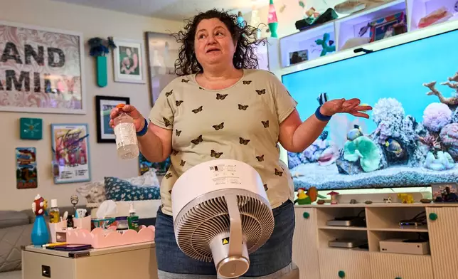 Tracy Rand uses a fan to help with her severe menopause symptoms, brought on after a surgery to remove her ovaries, at her home in Leesburg, Fla., Friday, Aug. 14, 2026. (AP Photo/Jacquelyn Martin)