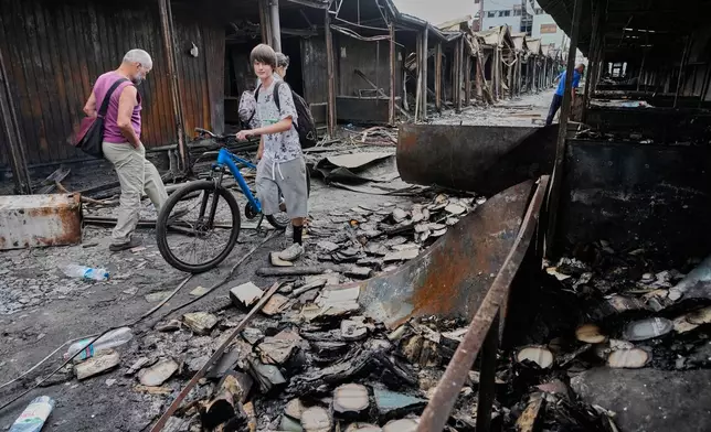People search for survived books after the fire on the site of the country's biggest book market, cased by Russia's recent missile attack in Kyiv, Ukraine, Wednesday, Aug.19, 2026. (AP Photo/Efrem Lukatsky)