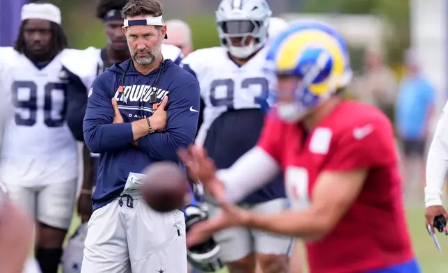 Los Angeles Rams quarterback Matthew Stafford, right, takes a snap as Dallas Cowboys head coach Brian Schottenheimer watches during an NFL football joint practice, Tuesday, Aug. 11, 2026, in Los Angeles. (AP Photo/Mark J. Terrill)