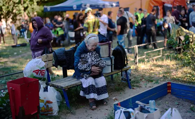 A woman whose grandson was killed during an overnight Russian missiles and drones attack sits on a bench in front of heavily damaged residential buildings in Kyiv, Ukraine, Thursday, Aug. 20, 2026. (AP Photo/Francisco Seco)