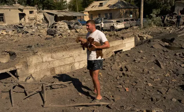 A man stands next to debris and destroyed cars after an overnight Russian missiles and drones attack, in Kyiv, Ukraine, Thursday, Aug. 20, 2026. (AP Photo/Francisco Seco)