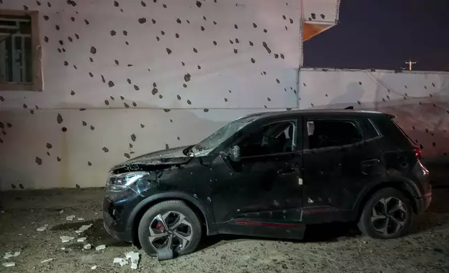A damaged car sits beside a wall bearing numerous impact marks near the site of a strike in Lamerd, southern Iran, Saturday, Feb. 28, 2026. (Alireza Ameri/Tasnim News Agency via AP)