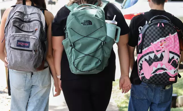 Middle school students Claire Knoth and Brockton Lozano and high school student Zoie Knoth walk with their backpacks Friday, July 31, 2026, in Flagstaff, Ariz. (AP Photo/Cheyanne Mumphrey)