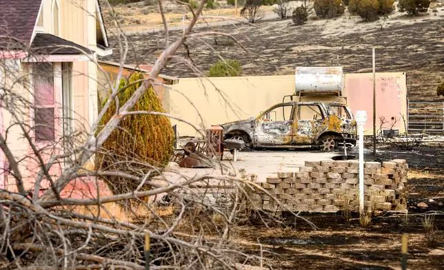 A scorched car sits outside a home that survived the Bug Fire near Reno, Nev., Thursday, Aug. 13, 2026. (AP Photo/Noah Berger)
