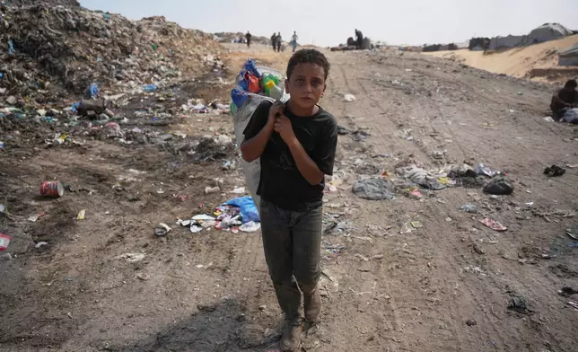 A Palestinian boy leaves a garbage dump after collecting combustible materials to use as fuel for cooking due to a shortage of cooking gas, in Deir al-Balah, central Gaza Strip, Saturday, Aug. 22, 2026. (AP Photo/Abdel Kareem Hana)