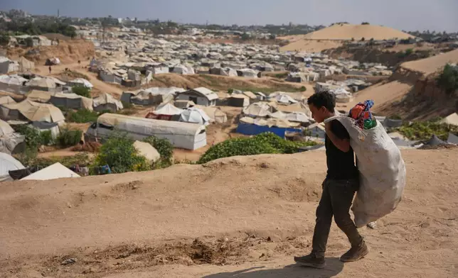 A Palestinian boy leaves a garbage dump after collecting combustible materials to use as fuel for cooking due to a shortage of cooking gas, in Deir al-Balah, central Gaza Strip, Saturday, Aug. 22, 2026. (AP Photo/Abdel Kareem Hana)