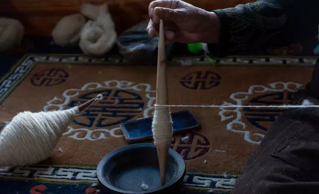 A worker pulls wool into a yarn at the Ethnic Huaji Handwoven Cooperative in Shannan in western China's Tibet Autonomous Region on July 23, 2026, as seen during a government organized visit for foreign journalists. (AP Photo/Ng Han Guan)